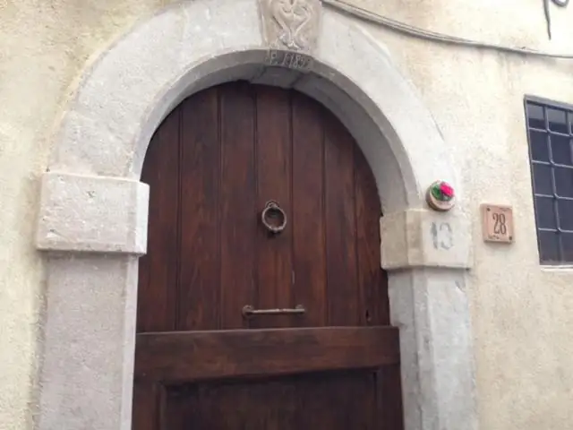 Portone in legno sotto un arco di pietra con la targa in ceramica del civico 28 di Via Buonconsiglio.