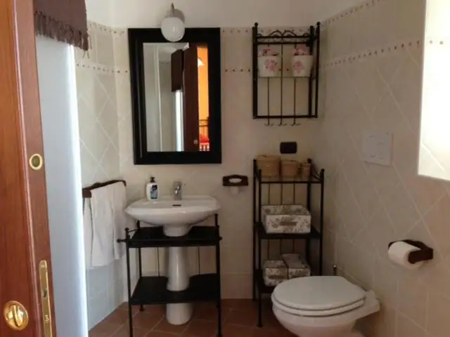 Bagno privato de Il Borgo 31 con lavabo, specchio dalla cornice scura, sanitari e piastrelle beige.