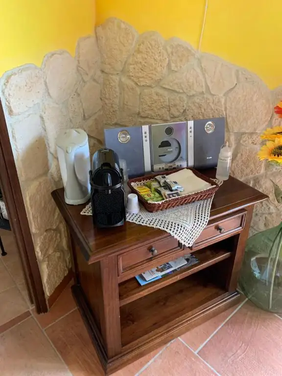 Angolo di cortesia de Il Borgo 31 su un tavolino in legno, davanti a una parete in pietra: bollitore, macchina del caffè e cestino con bustine.